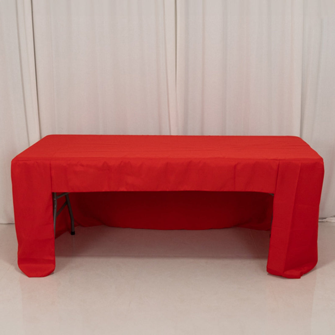 Red tablecloth draped over a folding table in a studio setting.
