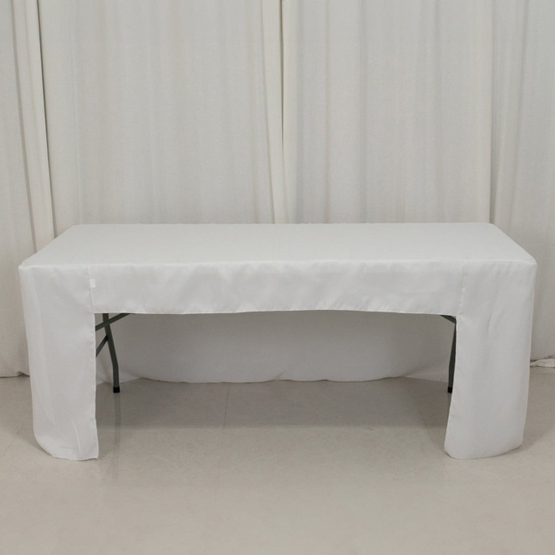 White table covered with a tablecloth in a studio setting.