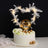 Birthday cake with heart-shaped feather decor and golden "Happy Birthday" sign.