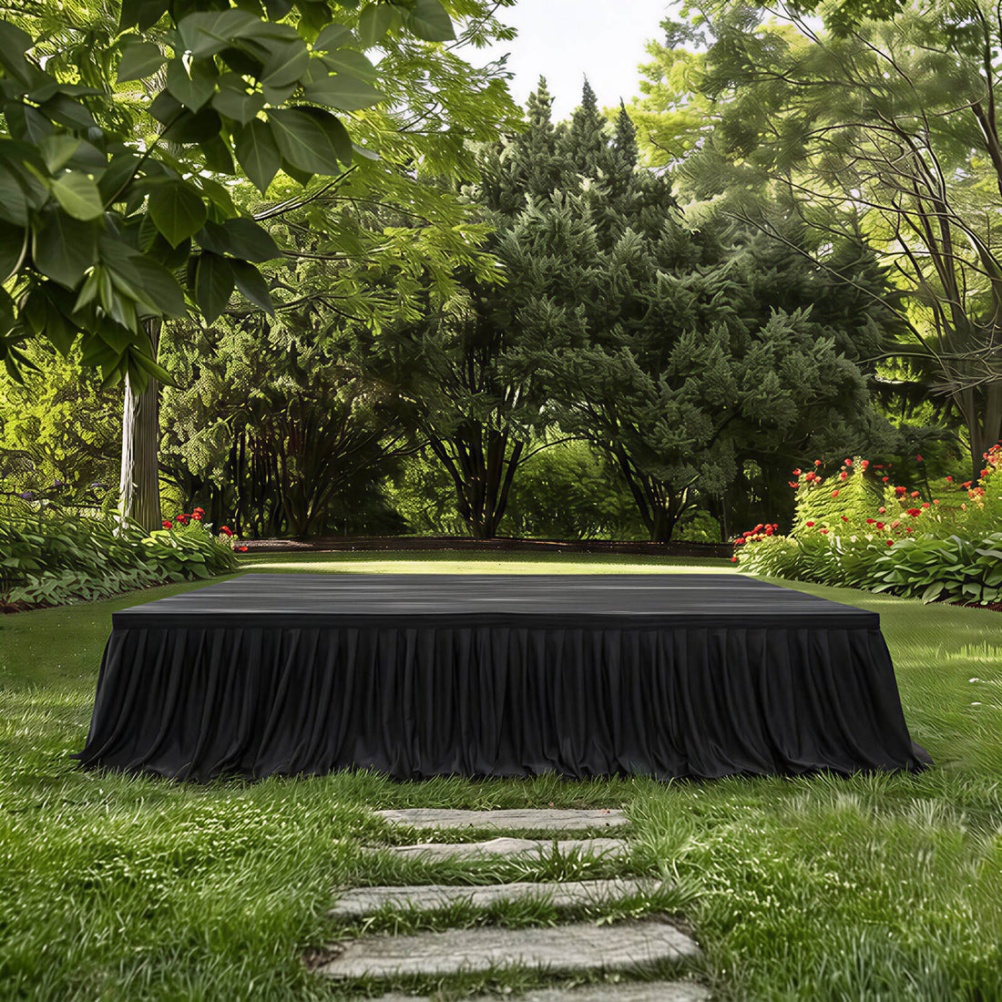 Outdoor black-draped stage in a lush garden with trees and flowers