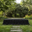 Outdoor black-draped stage in a lush garden with trees and flowers