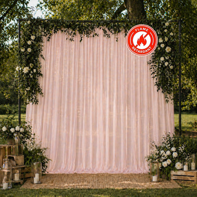 Outdoor floral wedding backdrop with pink drapes and fire retardant sign