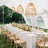 Outdoor wedding reception with a long table, floral centerpiece, and hanging pendant lights.