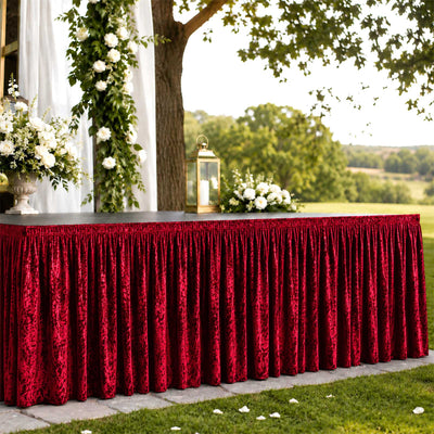 Outdoor wedding reception table with red velvet skirt and white floral decor
