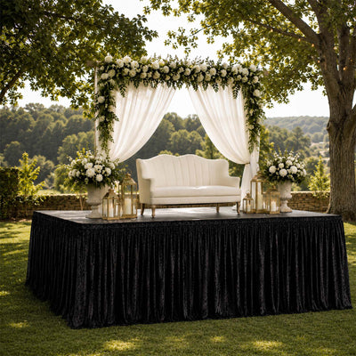 Outdoor wedding stage with floral arch, white loveseat, and lanterns