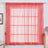 Sheer coral window curtain panel hanging in a bright room.