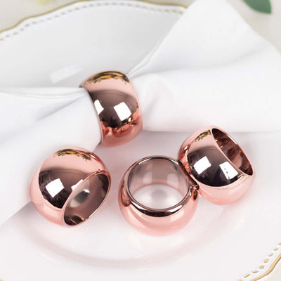 Rose gold napkin rings set on a white plate with a napkin.