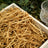 Shredded kraft paper filler in a wooden box with greenery and a glass nearby.