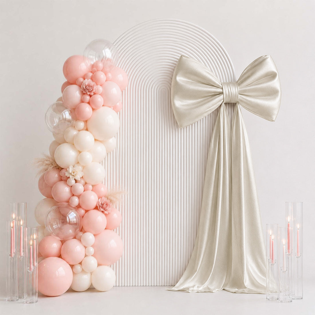 Pastel balloon arch with satin bow and candles for elegant party backdrop