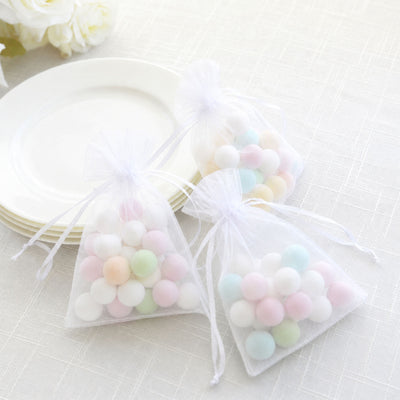 Pastel candy gift bags on white plates with soft floral decor