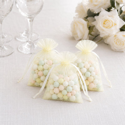 Pastel candy gift bags with white roses and champagne glasses on a table