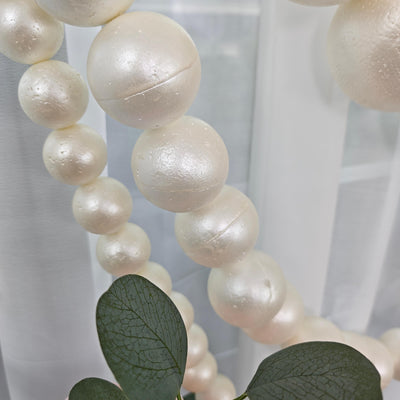 Pearl beaded garland with eucalyptus leaves against a soft white background