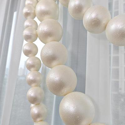 Pearl-white hanging spheres with sheer curtains, modern minimalist decor