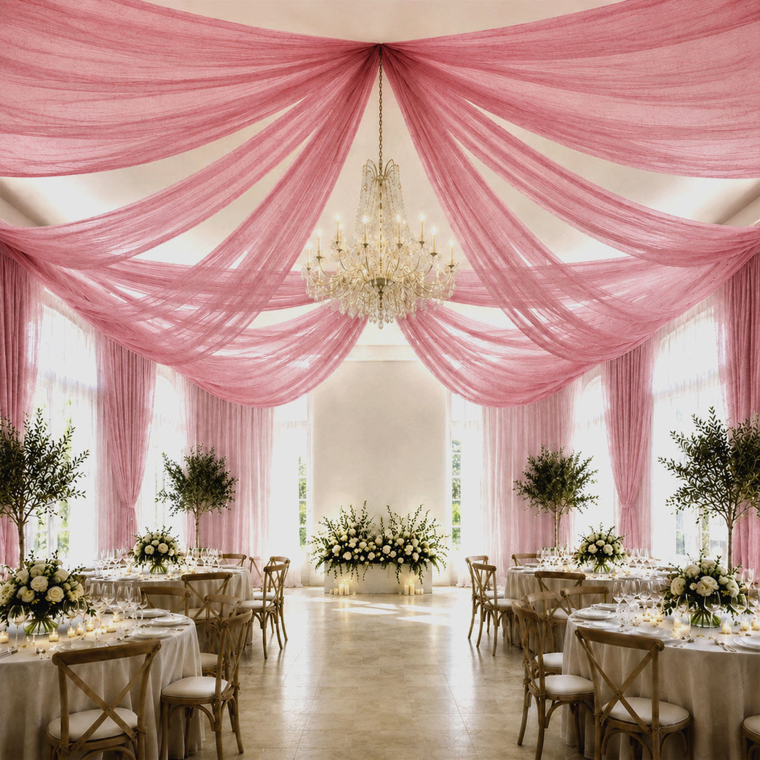 Pink draped wedding reception hall with chandelier and elegant floral tables