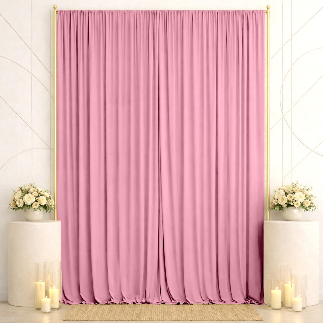 Pink event backdrop with elegant curtains, floral arrangements, and candles