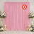 Pink event backdrop with white floral arrangements and candles, flame retardant curtain