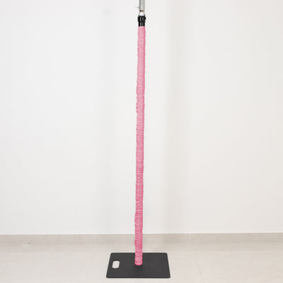 Pink padded pole on black base against white wall, minimalist studio equipment