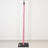 Pink padded pole on black base against white wall, minimalist studio equipment