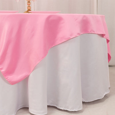 Round table with pink satin tablecloth draped elegantly over a white table skirt.