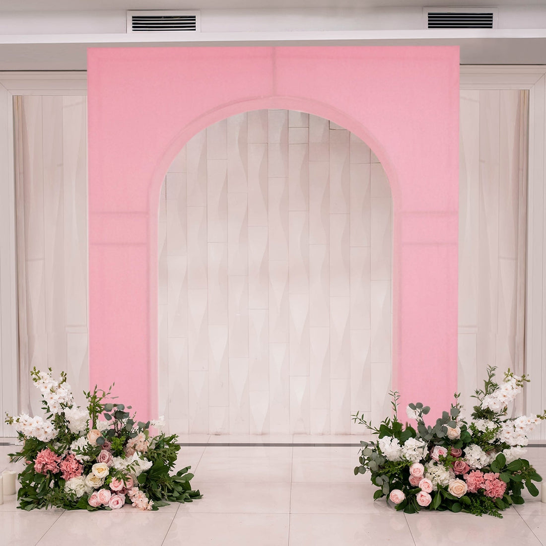 Pink arch backdrop with floral arrangements for events or photography.