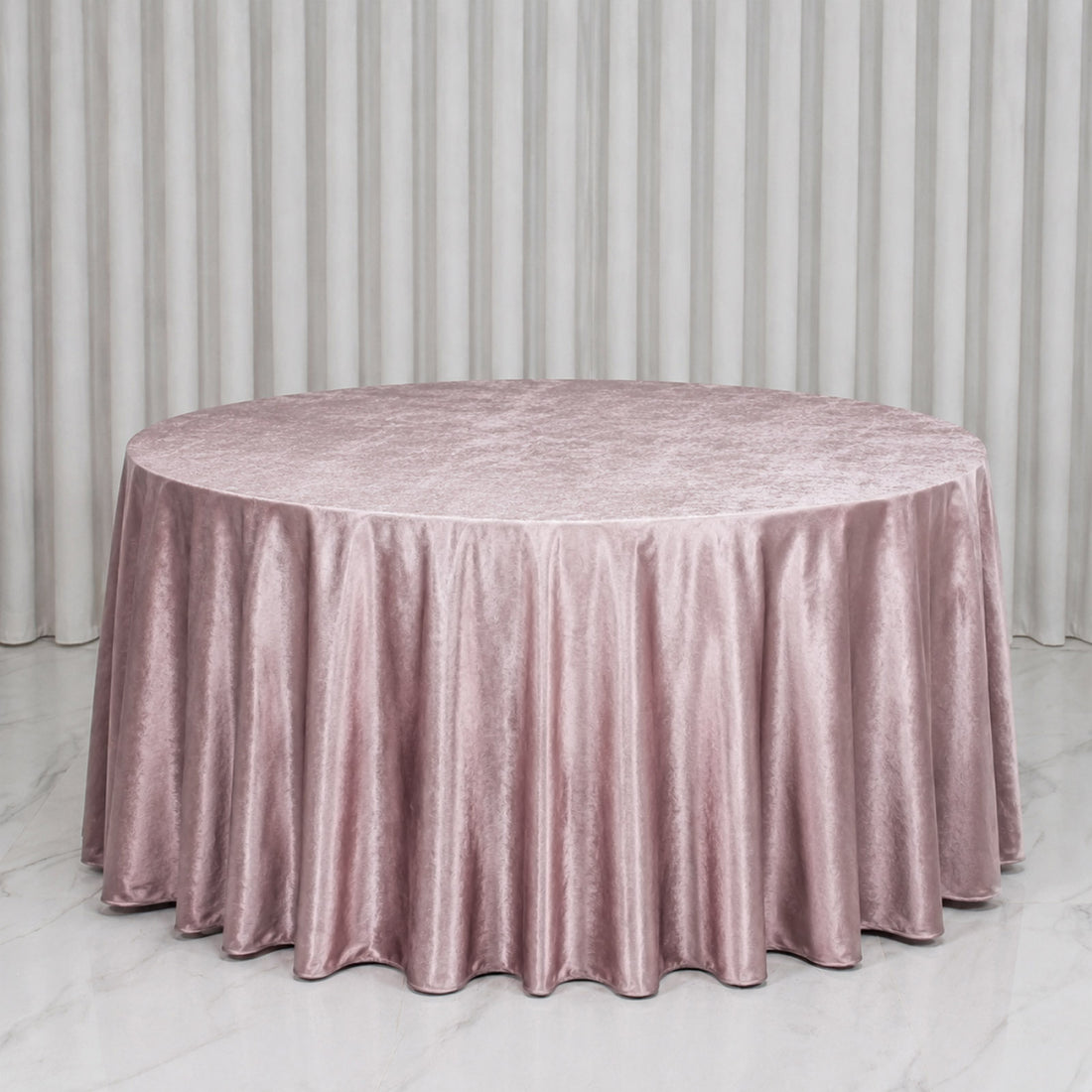 Pink velvet round tablecloth on a table with white curtains backdrop