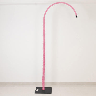 Pink wrapped curved floor lamp on black base against white wall