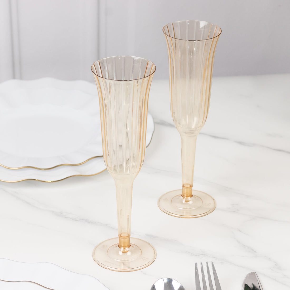 Elegant champagne flutes with gold rim on a marble table