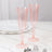 Pink ribbed champagne flutes on a marble table setting.
