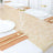 Elegant beige table runner with gold accents on a dining table setting.