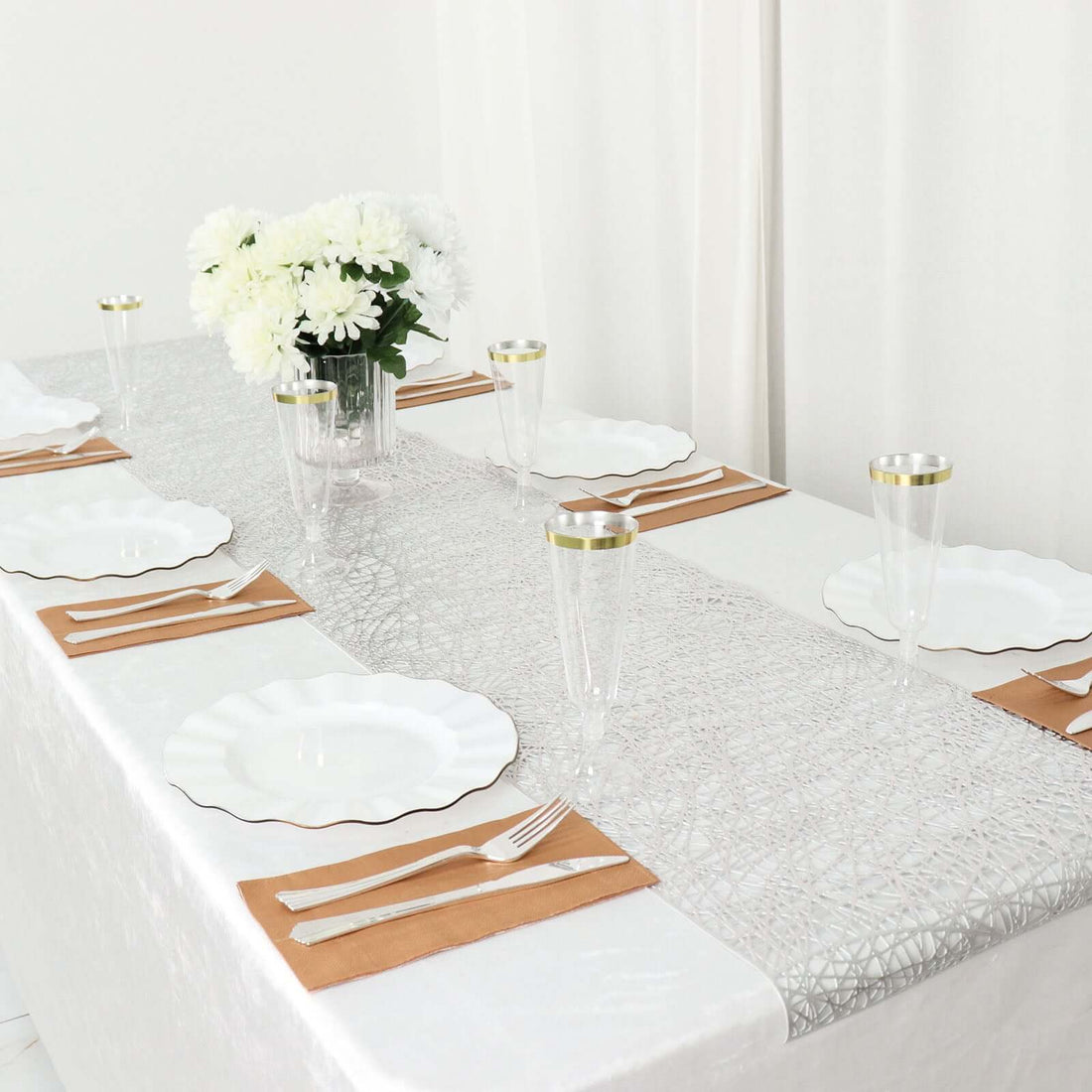 Elegant table setting with white plates, gold accents, and floral centerpiece.