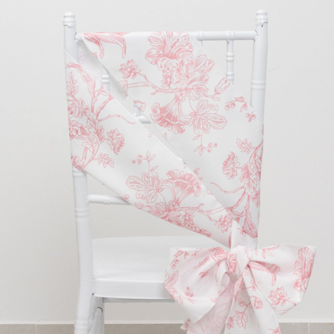 Pink floral chair sash draped elegantly on a white chair.