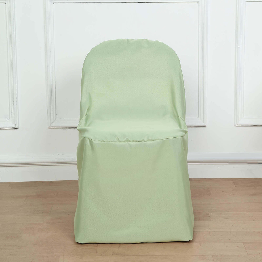 Green chair cover on a plain chair against a light backdrop.