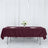 Elegant burgundy tablecloth on a dining table with floral centerpiece and wine glasses.
