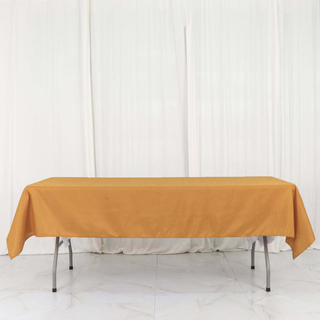 Orange tablecloth draped over a folding table in a studio setting.