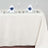 Elegant dining setup with white plates, blue napkins, and glasses on a cream tablecloth.
