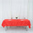 Red tablecloth elegantly draped on a table set for dinner with wine glasses and flowers.