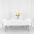 Elegant dining table setup with white tablecloth and floral centerpiece.