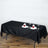 Black tablecloth draped over a dining table set with plates and glasses.