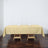 Beige tablecloth draped over a wooden table with glasses and napkins.