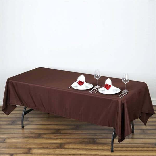 Brown tablecloth draped over a table set for two with plates and glasses.