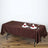 Brown tablecloth draped over a table set for two with plates and glasses.