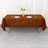 Brown tablecloth draped over a table with plates and a vase of flowers.