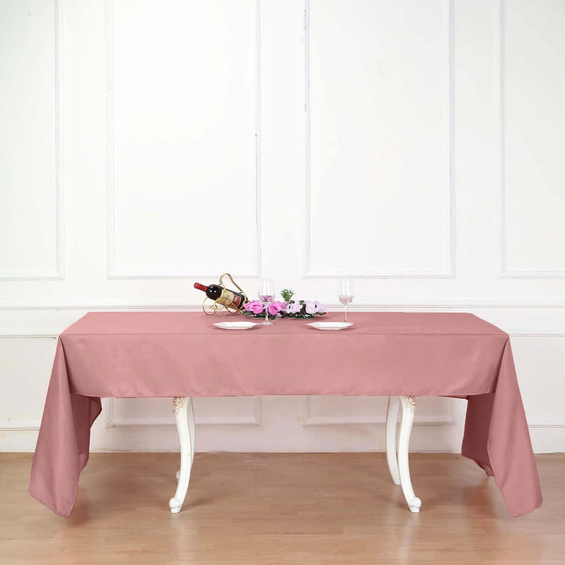 Pink tablecloth draped over a dining table with wine and plates