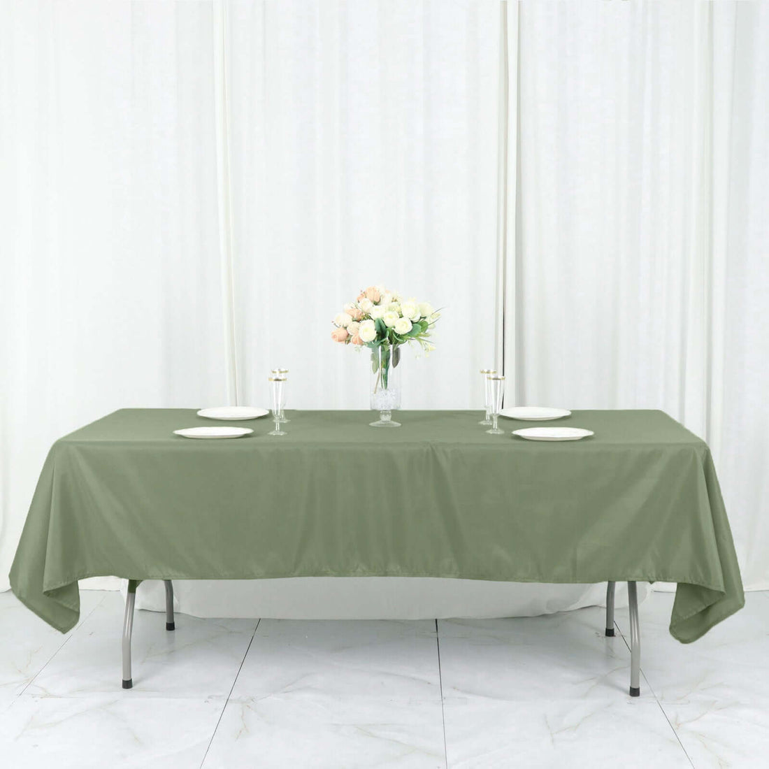 Olive green tablecloth on a dining table with floral centerpiece and plates.