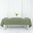 Olive green tablecloth on a dining table with floral centerpiece and plates.