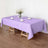 Lavender tablecloth draped over a wooden table set for dining.