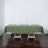 Green tablecloth draped over a wooden table with glasses and napkins.