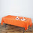 Orange tablecloth draped over a table set with plates and napkins.