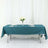 Teal tablecloth on folding table set with plates and flowers.