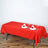 Red tablecloth draped over a table, set with plates, napkins, and glasses.